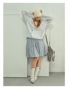 Dettaglio di un berretto in maglia beige abbinato a felpa grigia e gonna tutu azzurra