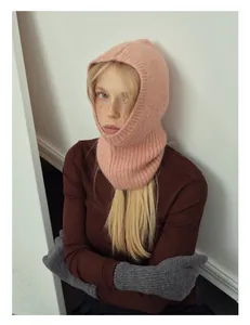 Dettaglio del passamontagna rosa in lana alpaca con guanti grigi e maglione marrone