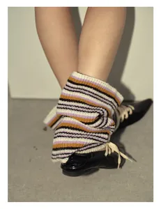 Detail of colorful striped wool knit leg warmers paired with black patent leather shoes