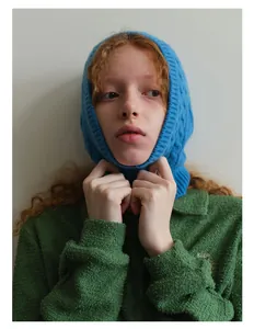 Close-up of blue cable-knit balaclava hood with green embroidered polo shirt