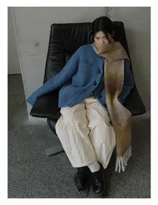 Dettaglio di sciarpa in lana sfumata abbinata a cardigan blu con bottoni ad alamaro