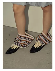 Detail of colorful striped wool knit leg warmers paired with black patent lace-up flats