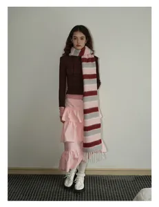 Détail d'une écharpe en laine à rayures colorées et franges avec une jupe rose à volants