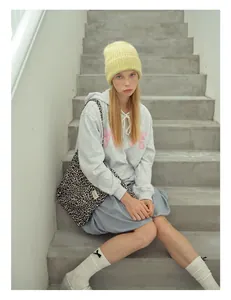Dettaglio di berretto giallo a maglia con felpa, borsa leopardata e scarpe piatte argento