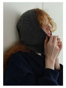 Detail of dark grey wool blend balaclava with cable knit pattern on a model