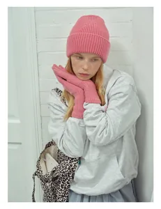 Detailed texture of thick pink knitted wool beanie and matching gloves on model
