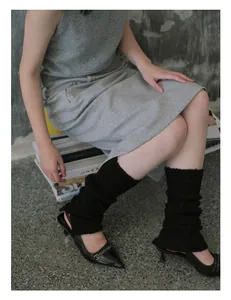 Close-up of black ribbed knit leg warmers styled with pointed-toe stiletto heels