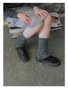 Close-up of gray knit leg warmers paired with classic black lace-up leather shoes