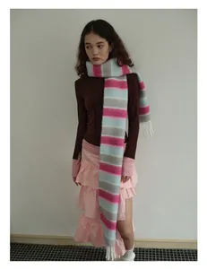 Détail d'une écharpe en laine à rayures colorées et franges sur la tenue d'hiver du modèle