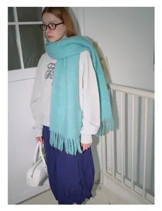 Full view of light blue wool scarf with long tassels paired with grey sweatshirt