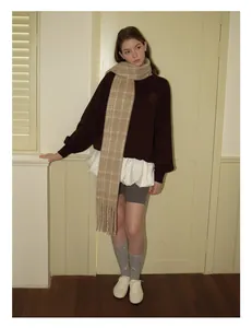 Detail of wool blend red plaid scarf styled with a brown sweatshirt and white pleated skirt