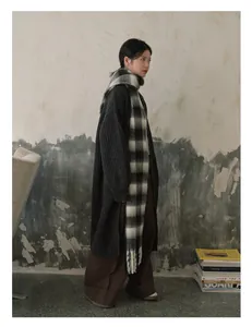 Winteroutfit met een oversized geruite sjaal met franjes en gebreid vest