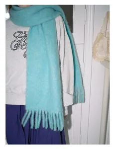 Close-up of thick light blue wool scarf with long tassels showing fuzzy texture and drape