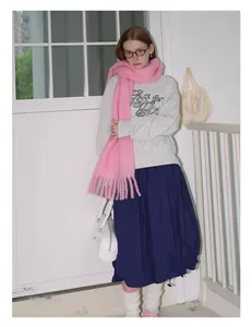 Full view of pink wool tassel scarf paired with grey sweatshirt and blue skirt