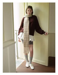 Full view of long beige plaid tassel scarf styled with cozy autumn sweatshirt and socks