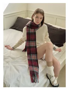 Detailed view of the classic plaid wool scarf with long tassel trim in a cozy bedroom setting