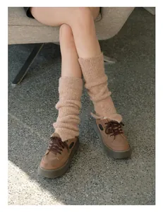 Macro view of knit leg warmers in pink mix paired with brown platform leather shoes