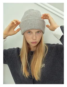 Detail of light gray ribbed knit wool beanie with premium metal PB logo brooch