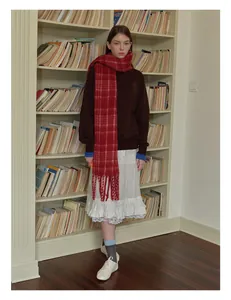Detail of red plaid wool blend scarf with fringe paired with a brown sweatshirt and lace skirt