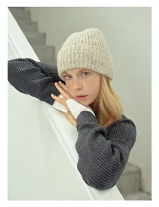 Dettaglio di un berretto beige in misto lana abbinato a un maglione grigio
