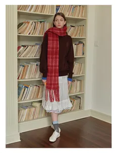 Detail shot of the long red plaid scarf with tassel trim and soft wool texture