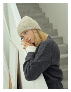 Dettaglio di un cappello in maglia a coste beige e un cardigan in lana grigio intrecciato