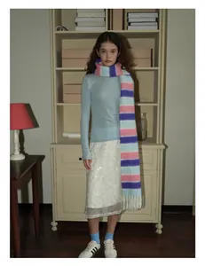 Détail d'une écharpe rayée en laine mélangée avec un pull bleu et une jupe blanche