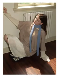 Detail eines dünnen hellblauen Wollstrickschals kombiniert mit einem Spitzenkleid
