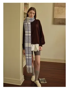 Winter look with blue plaid wool blend scarf and deep red sweatshirt in a cozy room