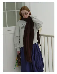 Close-up of thick brown wool scarf with tassels paired with grey sweater and long skirt