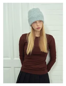 Dettaglio del berretto in alpaca azzurro con top in maglia marrone su una modella
