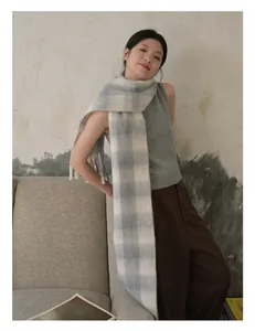 Detail van lichtblauw en beige geruite wollen sjaal met franjes op een lifestyle-model
