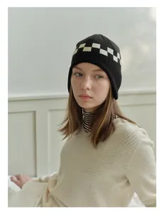 Close-up of black and white checkerboard knit pattern on soft winter earflap beanie