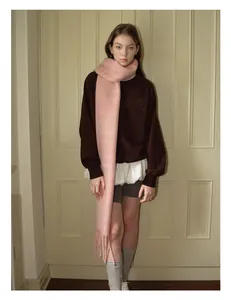Detailed view of light pink wool blend scarf featuring soft tassels and plush texture