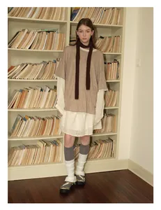 Retro-Outfit mit braunem Wollschal und Erdtönen im Lagenlook vor einem Bücherregal