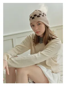 Close-up of knit texture and checkerboard pattern on the warm beige beanie hat