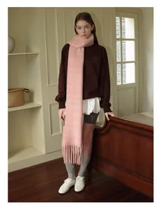 Detail of pink plaid tassel wool blend scarf styled with brown sweater and white skirt