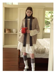 Detail of wool blend narrow scarf paired with brown knit top and vintage red camera