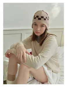 Close-up of khaki knit beanie with checkered pattern and ear flaps for winter fashion