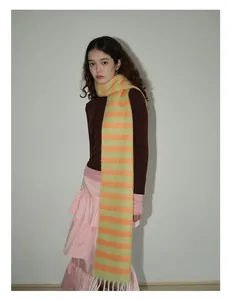 Détail d'une écharpe rayée vert clair et orange en laine avec franges blanches