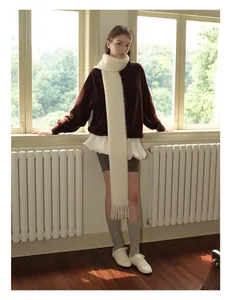 Dettaglio di una lunga sciarpa bianca in misto lana mohair con frange su abito casual