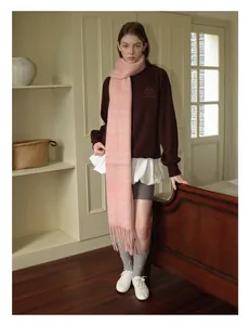 Close-up of pink plaid wool blend scarf with tassels styled over a brown sweatshirt