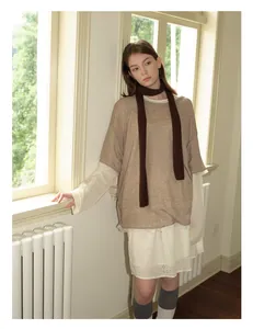 Detaillierte Strickstruktur eines braunen Wollpullovers über einem Spitzenkleid