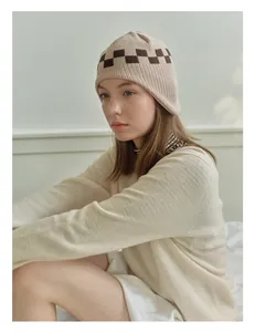 Detail of checkered knit beanie featuring beige and brown rib-knit texture and soft pattern