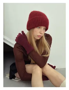 Dettaglio del set berretto e guanti in lana di alpaca in maglia rosso scuro