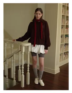 Modischer roter Wollstrickschal kombiniert mit braunem Oversize-Pullover im Retro-Stil