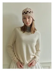 Close-up of checkerboard knit beanie and matching beige wool sweater for winter