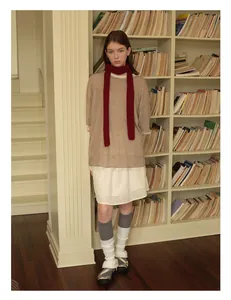 Detail eines roten schmalen Wollschals kombiniert mit Strickpullover und Spitzenrock