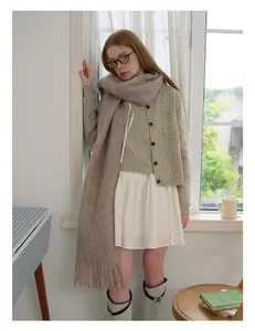 Detail of wool blend scarf with fringe paired with oversized cardigan and pleated skirt
