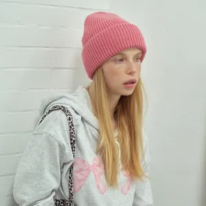 Pink wool knit beanie for women in soft ribbed texture paired with a grey hoodie
